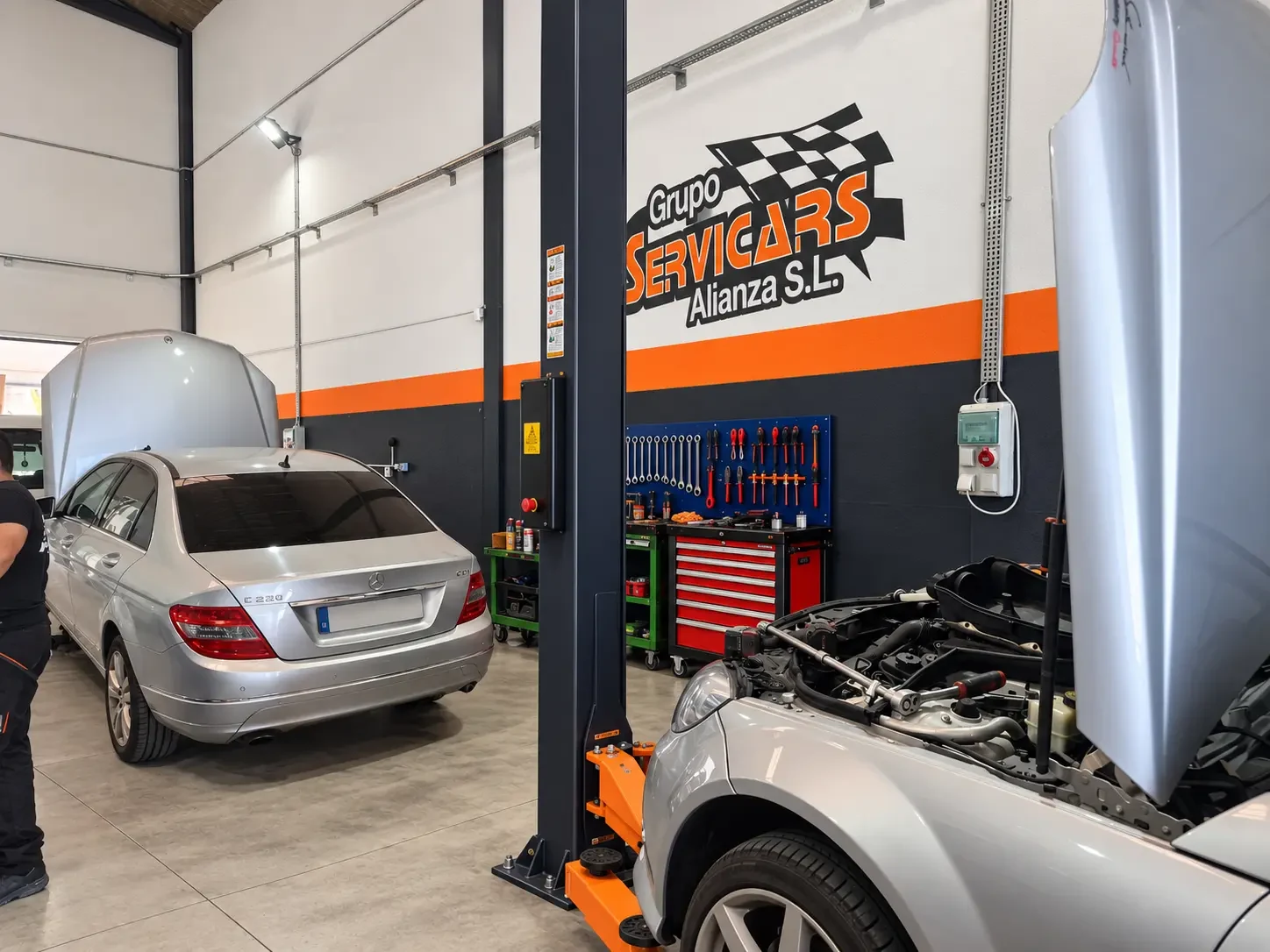 Zona de reparación de motores con capós abiertos y elevador en el taller SERVICARS